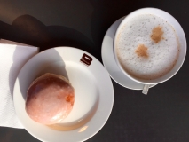 Perfekte Zwischenmahlzeit: Milchkaffee mit Berliner gefüllt mit Pflaumenmarmelade