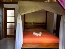 Hohe Decke, Freiluftbadezimmer und ein Bett mit Mückenschutz