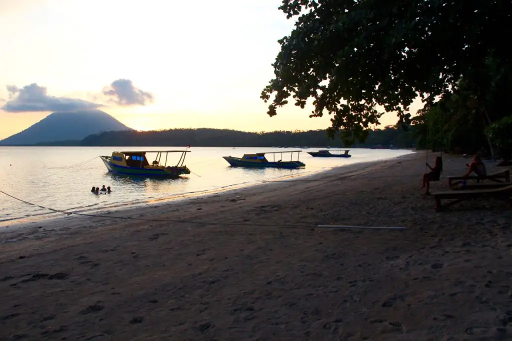 Der einsame Strand an der Westseite Bunakens: im Hintergrund die Insel Manado Dua mit dem Vulkan, mittag: die kleinen Boote der Panorama-Tauchbasis