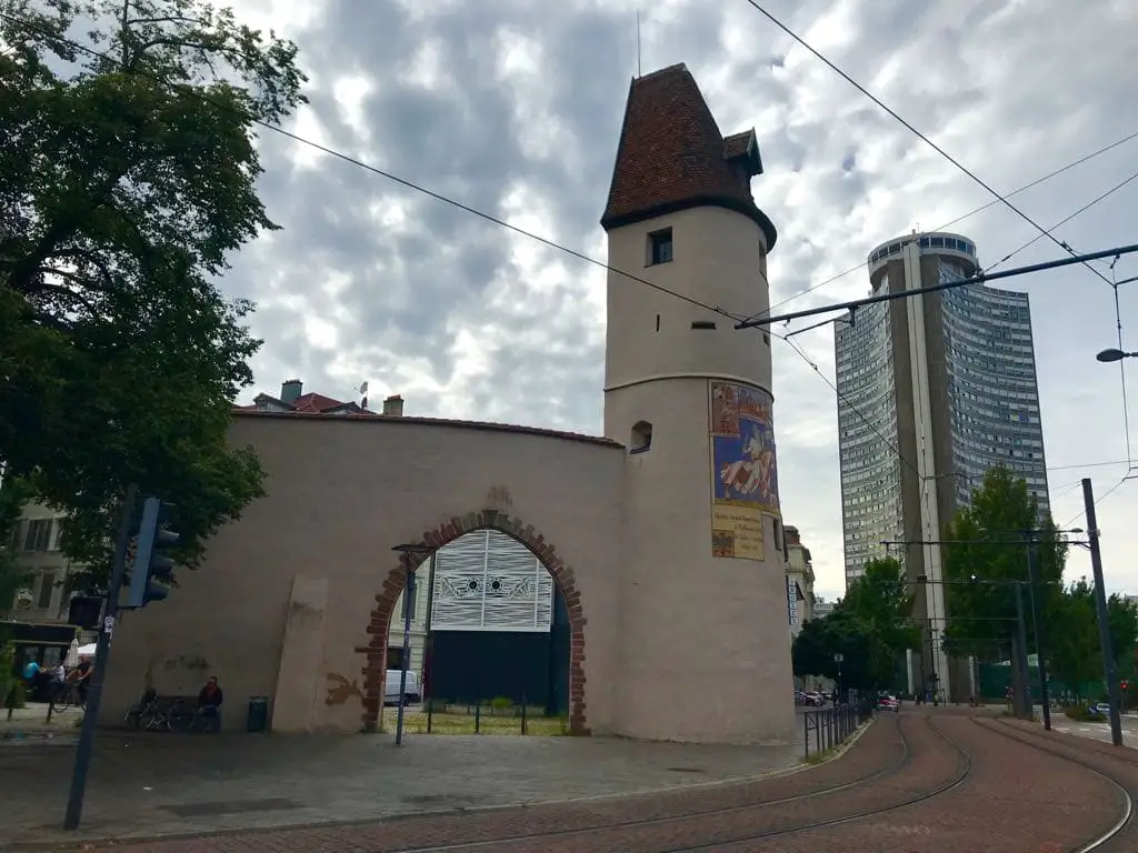 Ein altes Stadttor und rechts das Hochhaus Europaturm mit seinen drei Seiten.