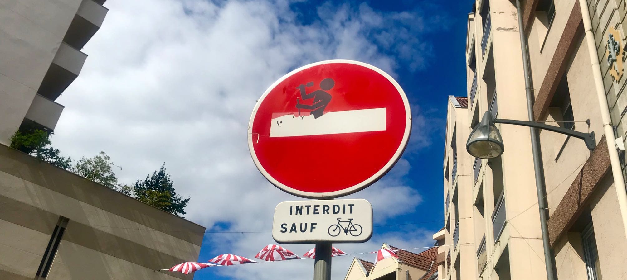 Straßenschild mit Sticker von Clet in Mulhouse